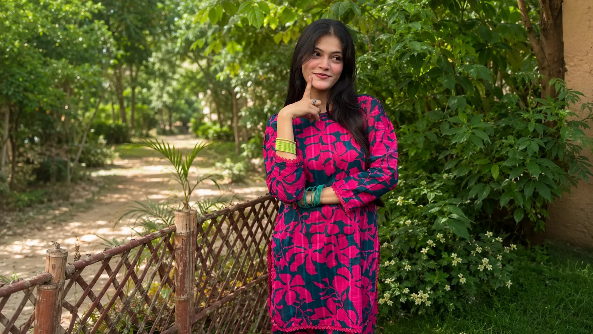 Woman wearing a vibrant pink and teal printed outfit in a green garden